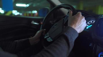 hombre conducción en innovador automatizado coche utilizando auto-estacionamiento piloto automático para estacionamiento en estacionamiento lote. robótico computadora torneado rueda en autodirección modo video