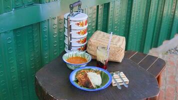 a serving of rice, eggs, chicken, gravy in a bowl and a glass of cucumber drink photo