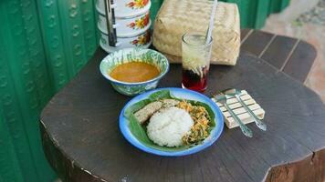 a serving of rice, eggs, chicken, gravy in a bowl and a glass of cucumber drink photo