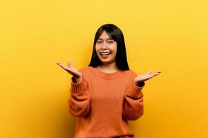 asian girl Pretty wearing an orange casual dress. yellow background Celebrate the victory with a happy smile and the winner's expression with a raised hand. happy expression photo