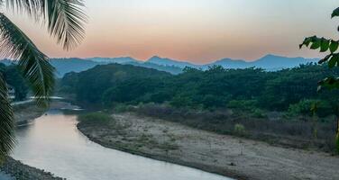 Sunset over the mountains with river and palm tree photo