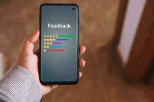 Woman hand holds a smartphone with consumer reviews interface on screen. Rating service. Online application for customers satisfaction. Feedback survey concept. photo