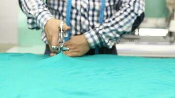 Sastre cortes pedazo de tela con tijeras, Sastre corte tela por medición con cinta medida en textil taller, selectivo atención video