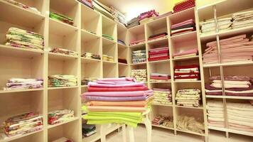 tecidos em prateleiras dentro têxtil loja, diferente estampado e colori tecidos estão em exibição dentro loja, seletivo foco video