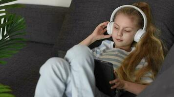 Little  girl listening to the music with the headphones and digital tablet. video