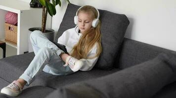 pequeño niña escuchando a el música con el auriculares y digital tableta. video