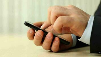 homme séance à table et en utilisant téléphone intelligent, homme émouvant mobile téléphone écran pour gros voir, sélectif concentrer video