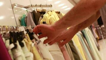 Colorful and patterned women's clothes in women's clothing store, customer in store looking at clothes on hanger and buying, selective focus video