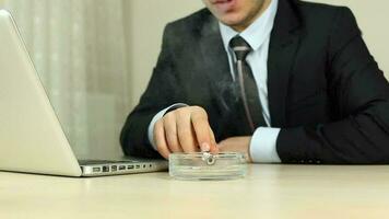 Businessman with suit smokes and working from computer in office, man working from computer typing text while smoking in office, selective focus video