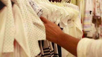 Clothes for babies on display in children's clothing store, customer looking at clothes for little baby girls buys an outfit, selective focus video