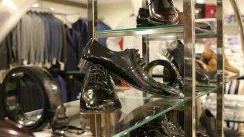 espuma clássico sapatos e acessórios em exibição dentro masculino clássico roupas loja, cliente olhando para uma clássico couro sapatos para terno dentro homem roupas loja, seletivo foco video
