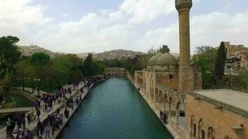 zumbido Disparo de histórico mezquita con Roca arquitectura y lago siguiente a él, mezquita arquitectura con verde arboles alrededor eso y construido con piedras, selectivo atención video