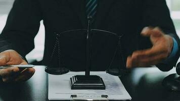 Business and lawyers discussing contract papers with brass scale on desk in office. Law, legal services, advice, justice and law concept picture with film grain effect video