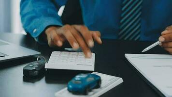 Closeup of Asian female signing car insurance document or lease paper contract or agreement. Buying or selling new or used vehicle with car keys on table. video