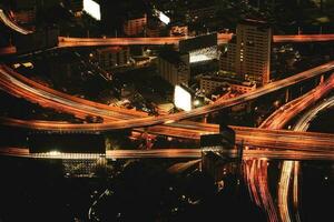 Aerial view of city at night with congested traffic on a multi-level expressway with a background of dense skyscrapers in the capital city of Bangkok, Thailand. photo