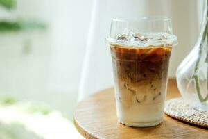 Fresco café, con hielo capuchino, macchiato, latté con separar Leche y café. café en el plastico taza en de madera mesa en café tienda foto