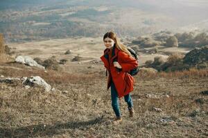 a traveler in a jacket jeans and boots climbs the mountains in nature landscape photo