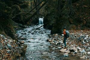 traveler with backpack landscape mountains transparent river pond and forest in the background photo