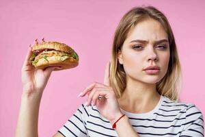 linda rubia niña en a rayas camiseta hamburguesa de cerca rápido comida estilo de vida foto