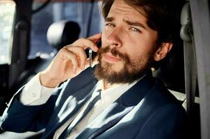 business man with a beard talking on the phone in a car trip photo
