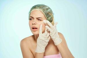 woman squeezes black dots on her face discontent blue background photo