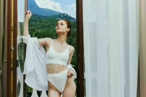 slender woman stands on a balcony terrace in lingerie sunlight beautiful view Summer day photo