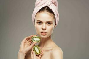 beautiful woman with pink towel on her head naked shoulders kiwi in hands health skin care photo