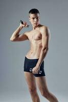 sporty man in black shorts with dumbbells in his hands posing photo