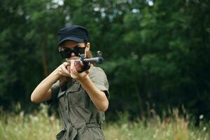 Military woman hold a weapon in your hands sunglasses aiming fresh air photo