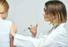 A woman doctor in a medical gown is giving an injection to a patient photo