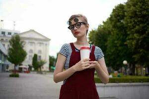 mujer con lentes en el calle hablando en el teléfono en un vaso con un bebida foto