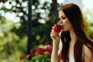 alegre mujer en un blanco vestir bebidas café al aire libre en un café inalterado foto