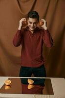 A man in a red shirt with oranges in his hands a mirror on the table photo