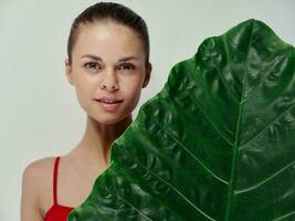 woman in a red swimsuit palm leaf Exotic attractive look light background photo