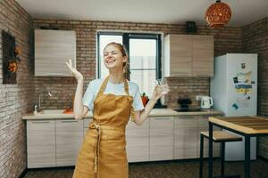 mujer en un marrón delantal vaso de agua cocina interior estilo de vida foto