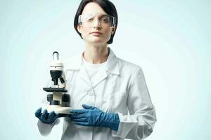 female laboratory assistant in a white coat with a microscope in the hands of a professional medicine technology photo