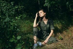 Woman with closed eyes sits on the grass in the forest green leaves photo