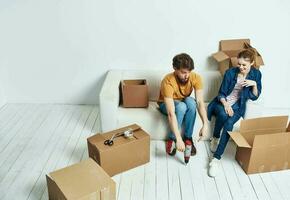 joven Pareja en blanco sofá con cajas de divertido chateando foto