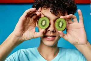 man with curly hair kiwi fruit holding fruit blue background photo