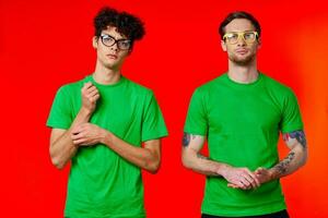 two friends are standing side by side in green T-shirts with glasses photo