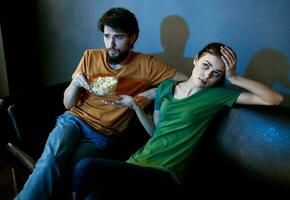 Handsome man and young woman on sofa indoors watching TV in the evening photo