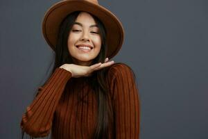 Brunette brown hat hand gestures brown sweater fashion emotions Gray background photo