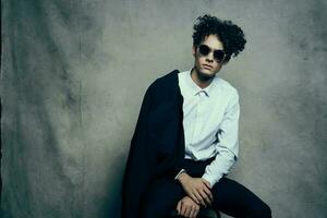 trendy guy with curly hair indoors on a fabric background and a jacket on the shoulder photo