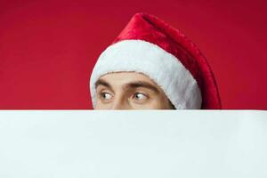 emotional man in a santa hat holding a banner holiday red background photo