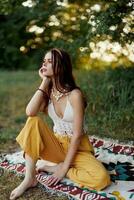 joven hermosa hippie mujer sentado en el suelo en naturaleza en el otoño en eco ropa en el puesta de sol luz, un estilo de vida de viaje y armonía con el mundo foto