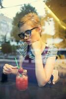 mujer en lentes con corto pelo se sienta en un café soledad cóctel descanso foto