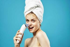 cheerful woman with a towel on her head massagers in hands dermatology clean skin photo