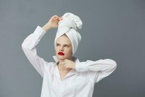 bonito mujer blanco camisa productos cosméticos con toalla en cabeza aislado antecedentes foto