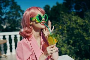 retrato de hermosa mujer en verde Gafas de sol con cóctel en verano al aire libre verano día foto