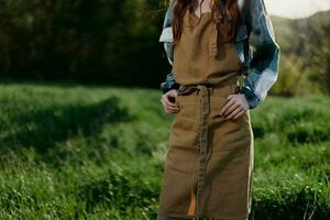 Close-up of a woman in a gardener's work apron against the green, fresh summer grass outdoors showing her hands photo